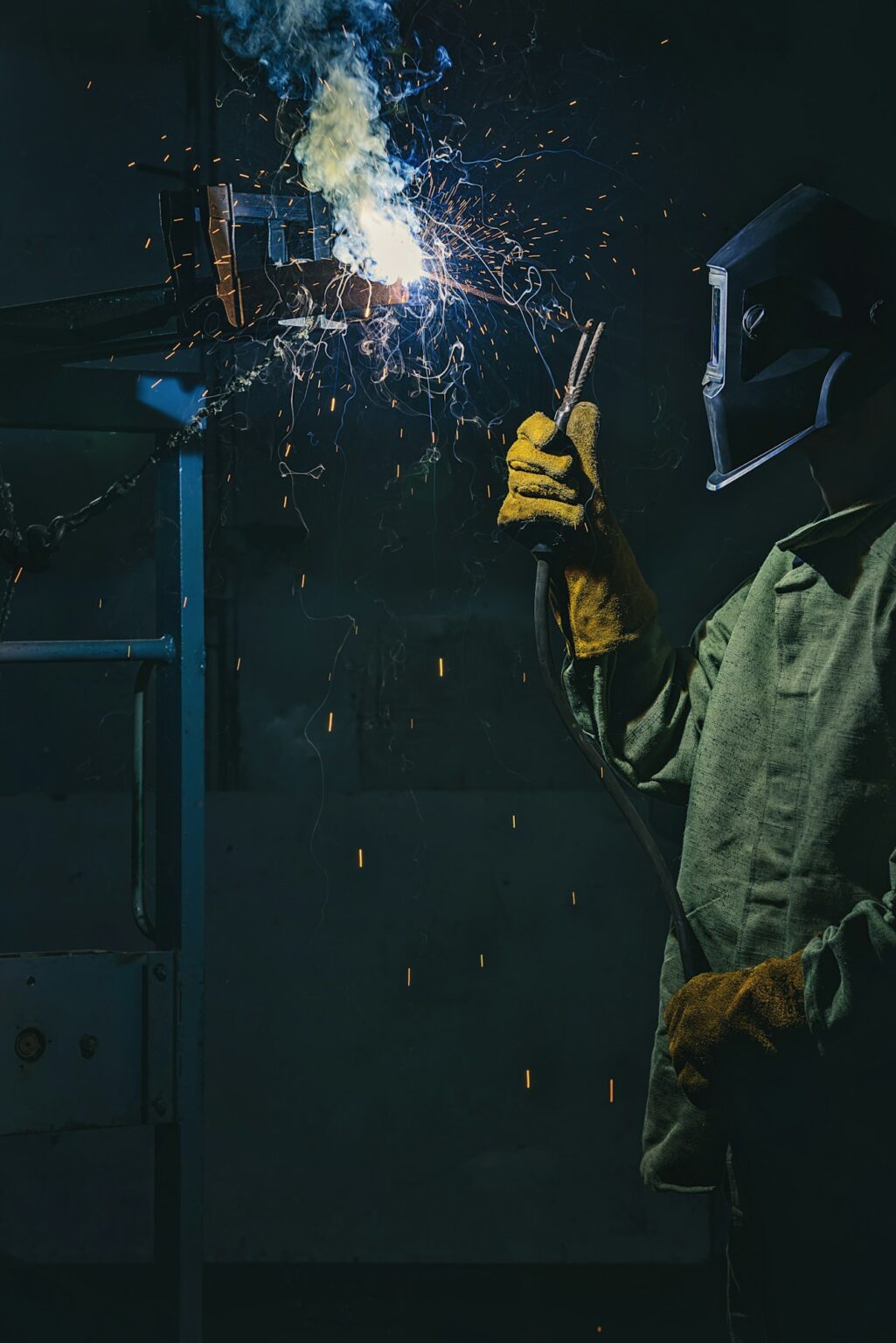 side view of manufacture worker welding metal with sparks at factory